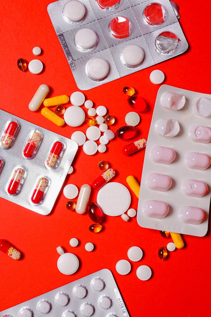 A close-up of various pills and capsules on a vibrant red background, highlighting healthcare and medicine.
